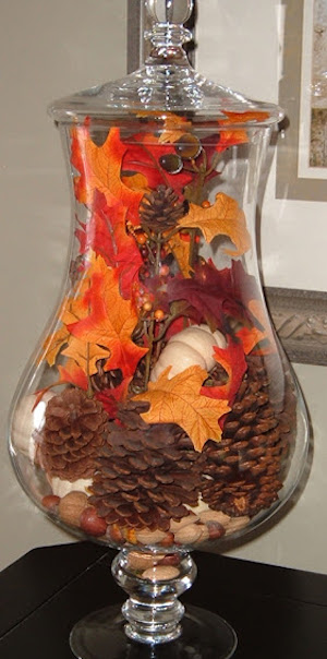 Apothecary jar filled with pinecones, fall leaves pumpkins, acorns
