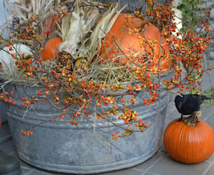 tina galvanizada llena de decoraciones de otoño para el porche