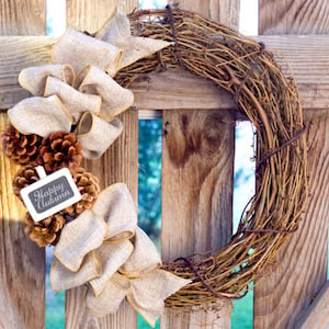 grapevine wreath with burlap ribbons and pinecones on the side