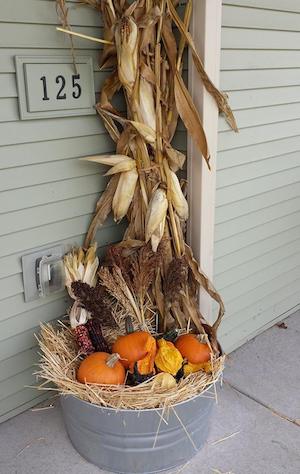 galvanized tub filled with hay, pumpkins, corn and cornstalks