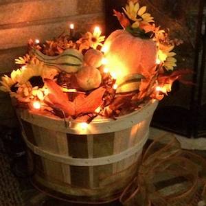 lit up Fall bushel basket with fall leaves, pumpkins and gourds