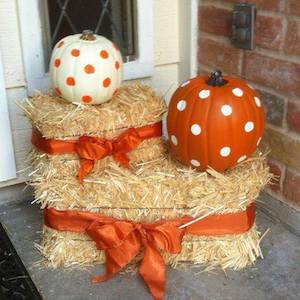 hay bales wrapped in bows and topped with polka dot pumpkins on the porch