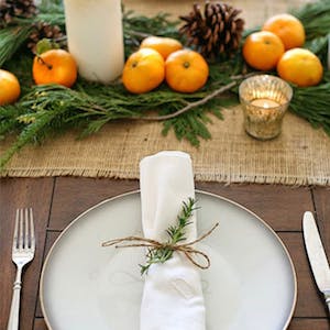 Holiday Table decorations with oranges, burlap, evergreen and pinecones 