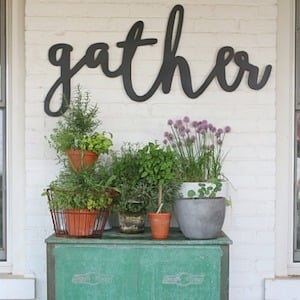 Gather Sign on wall with potted plants