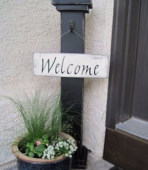 Welcome Column sign with potted plant by front door