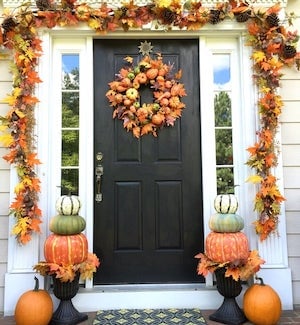 porche de otoño con puerta guirnalda de hojas de otoño, topiario de calabaza y corona de otoño