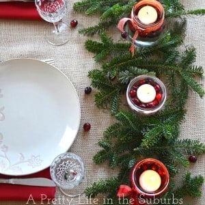 Simple and Pretty Christmas Centerpiece with evergreen and cranberries in candleholders