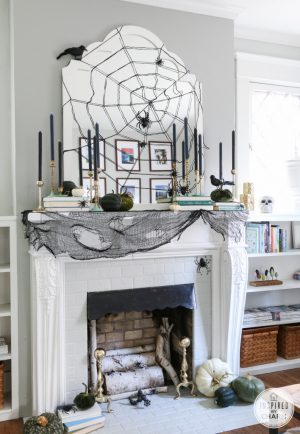 Spider web above the fireplace with black taper candles 