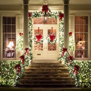 Luces navideñas tradicionales al aire libre y guirnaldas perennes con lazos
