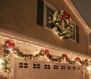 Guirnalda navideña iluminada y corona encima del garaje
