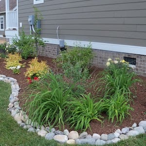 backyard DIY garden bed edging with river rocks