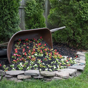 Tipped Wheelbarrow Planter lined with rocks flower garden backyard landscaping