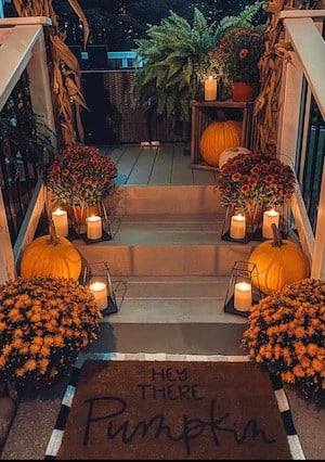 farmhouse fall porch with mums, pumpkins and candles