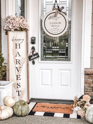 simple and neutral farmhouse fall porch decor with a harvest sign, chair and fall pillow