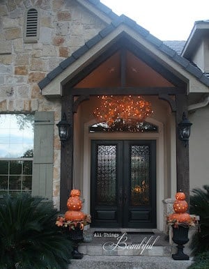 Iluminación otoñal del porche con formas de calabaza junto a la puerta principal