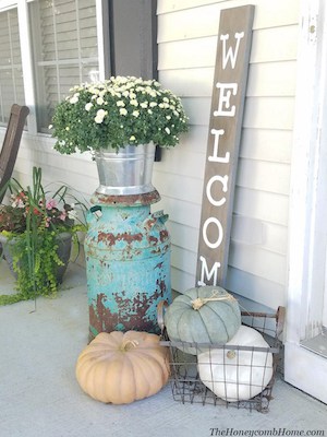front porch farmhouse decor with a welcome fall sign with mums in a olive bucket and white washed pumpkins