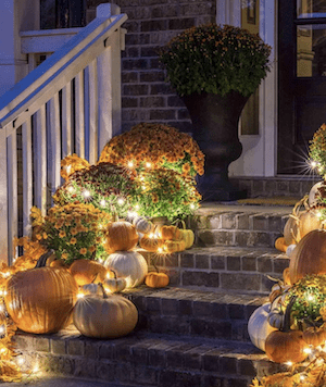 lit up pumpkins and mums for fall porch stairs