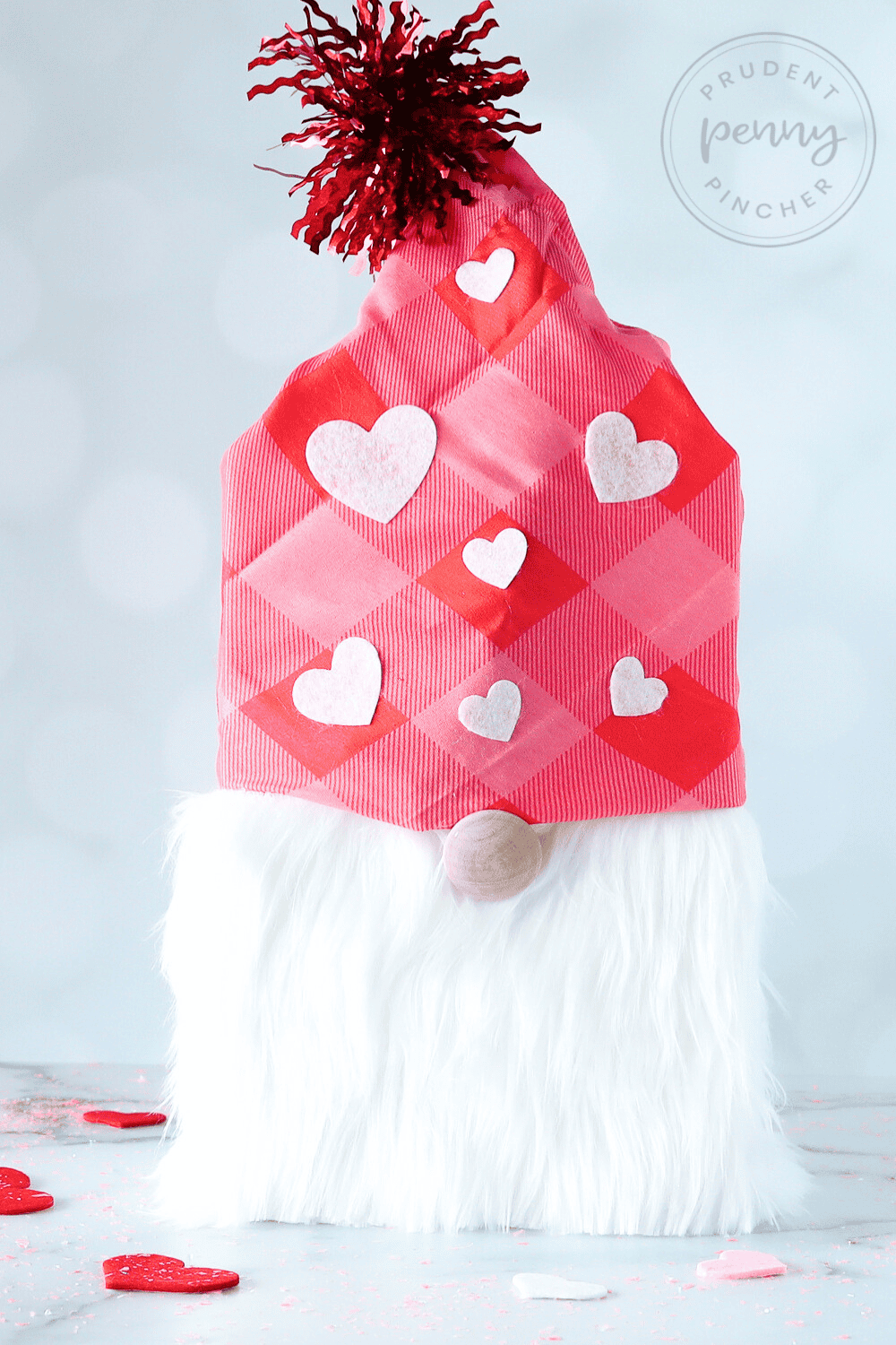 Gnome Valentine craft on a tabletop with scattered heart confetti,