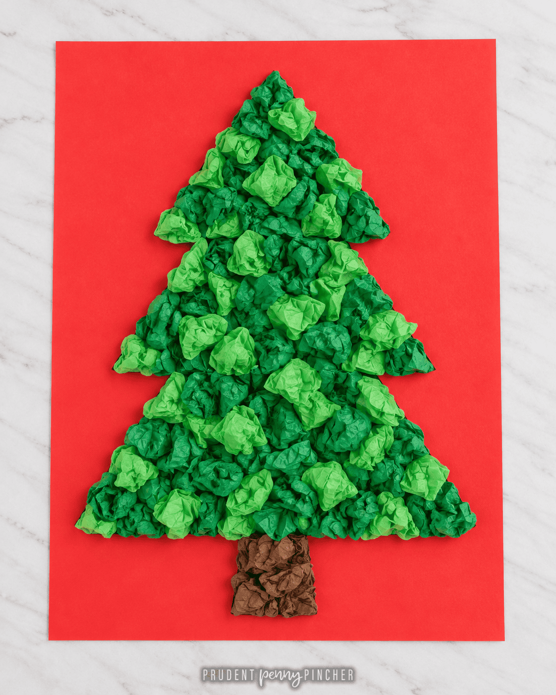 Christmas tree craft made with crumpled green tissue paper and a brown tissue paper trunk on red cardstock.